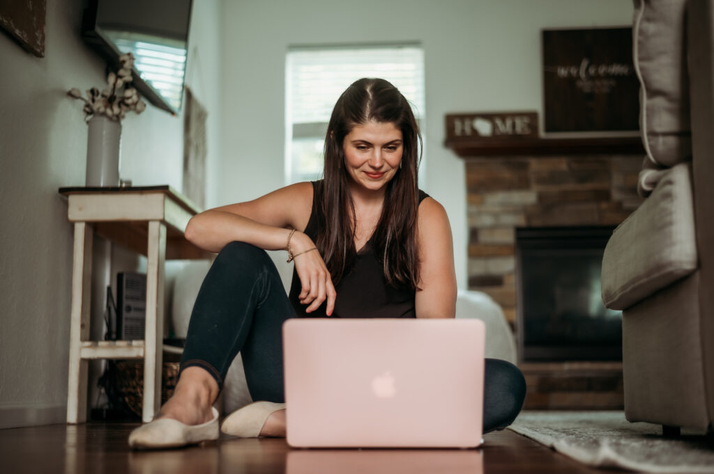 women sitting on a floor working on a laptop | social media feeds anxiety