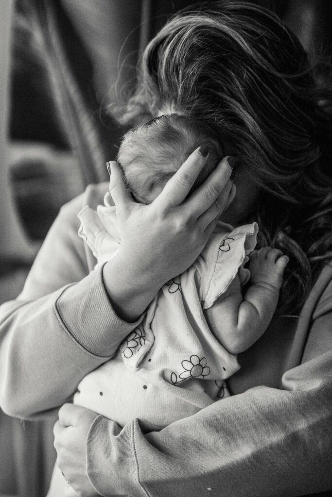 A mother holds her newborn close, her face obscured in a moment that reflects the emotional weight and intensity often associated with postpartum rage.