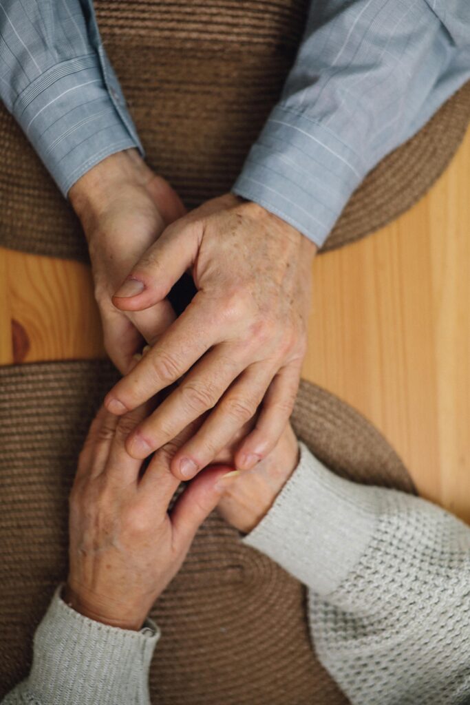 Two people hold hands across a table, symbolizing the comfort found in reassurance seeking.