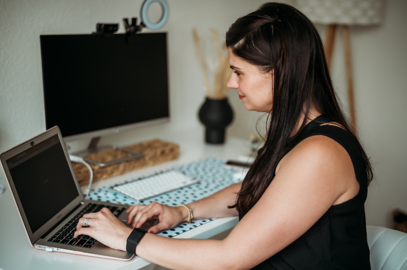 A woman works on a laptop in a home office.