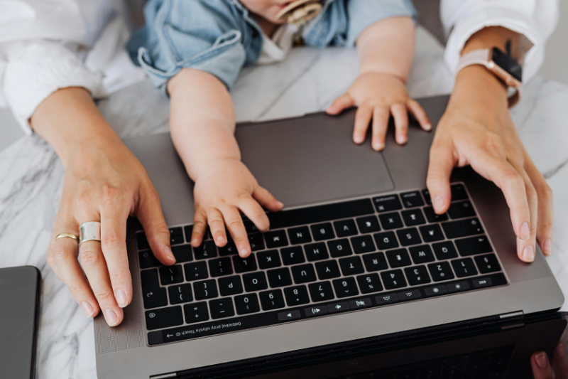 Close-up of a parent and baby’s hands on a laptop keyboard, symbolizing the challenges of managing anxiety and OCD as a working parent.