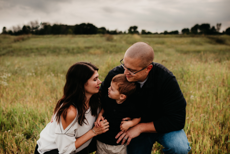 A family enjoys a quiet moment in a grassy field.