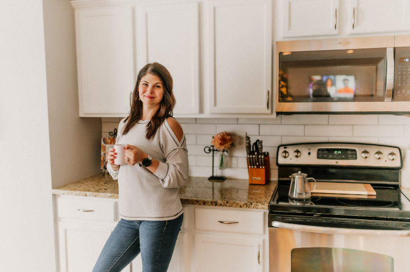 a person standing in a modern kitchen holding a coffee cup.