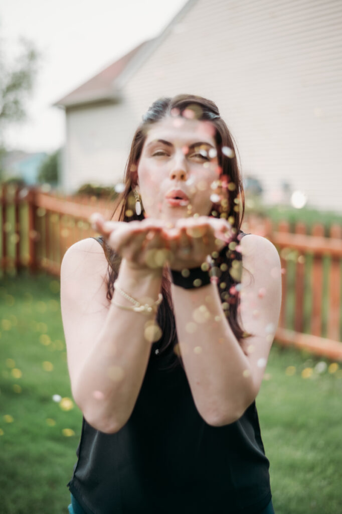 woman blows confetti at camera