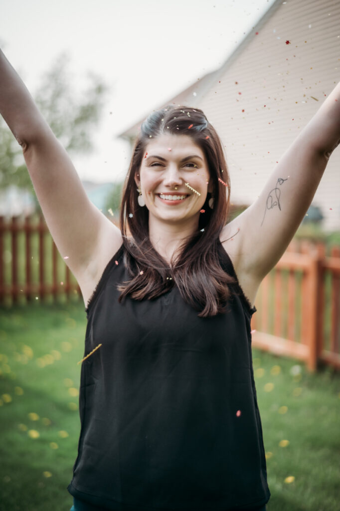 woman raises hands in the air celebrating
