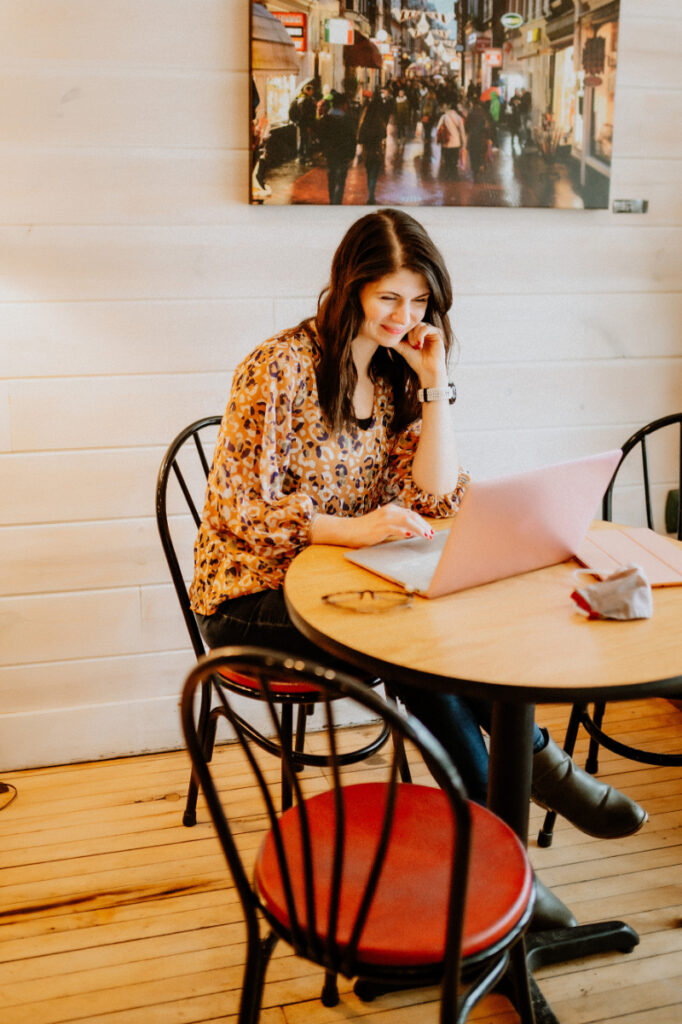 woman working on a laptop on kitchen table | how to be kind to yourself